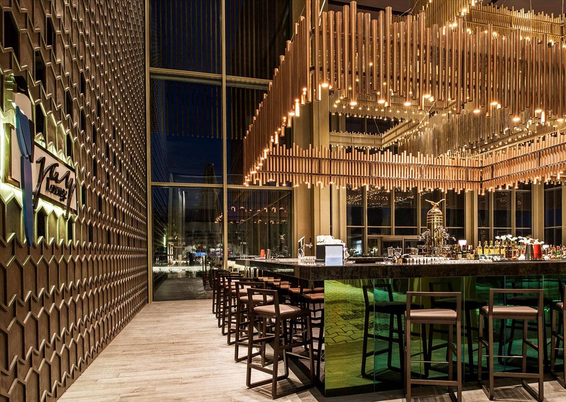 Innenansicht der Bar im Maxx Royal Kemer Resort mit geschwungener Theke und modernen Stühlen.