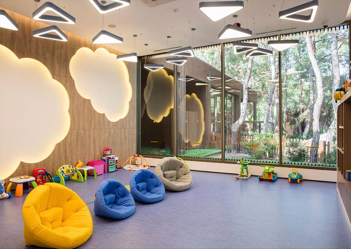 Kinderzimmer im Maxx Royal Kemer Resort mit bunten Sitzsäcken und Spielzeug vor großen Fenstern.