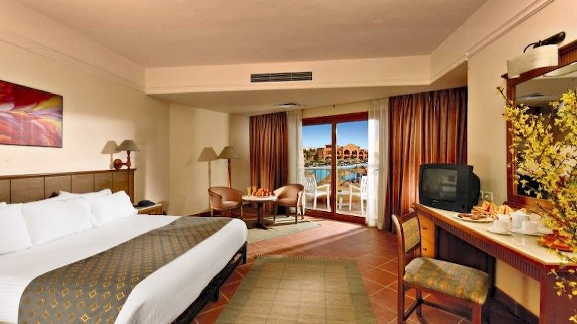 Zimmer im Charmillion Garden Aqua Park Hotel mit großem Bett, Schreibtisch und Balkon.