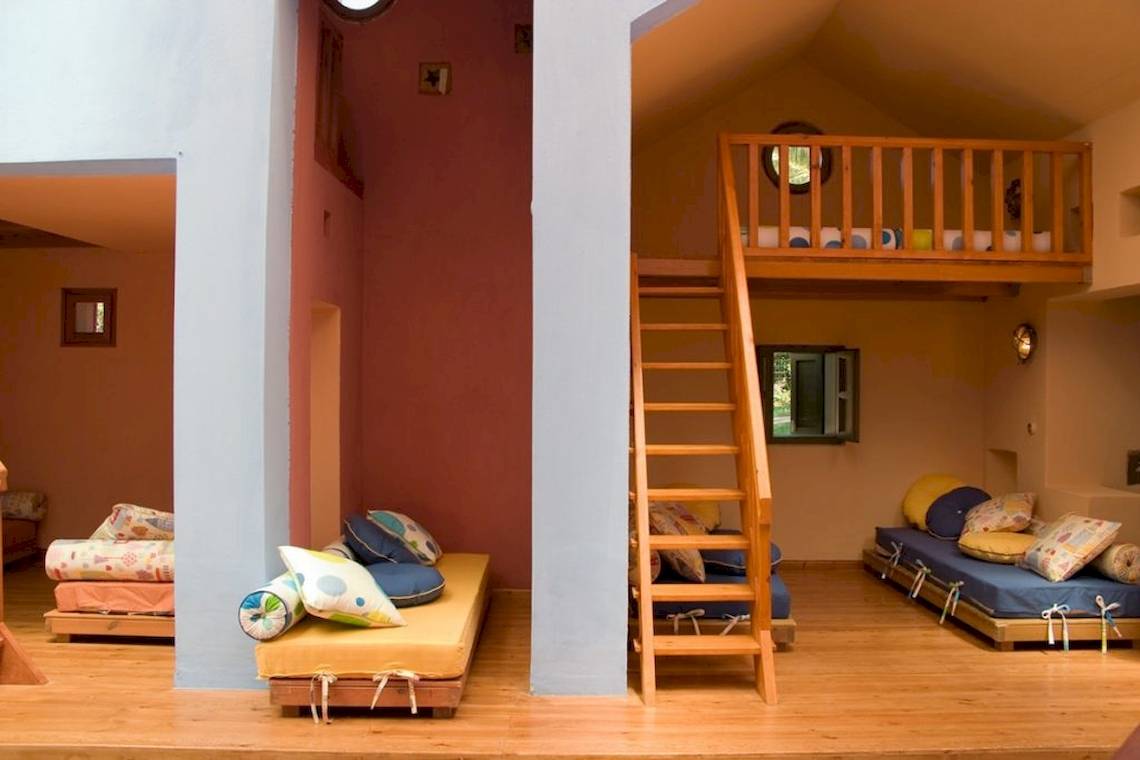 Innenansicht eines Schlafzimmers im Aquila Rithymna Beach Hotel mit bunten Kissen und Holzbetten.