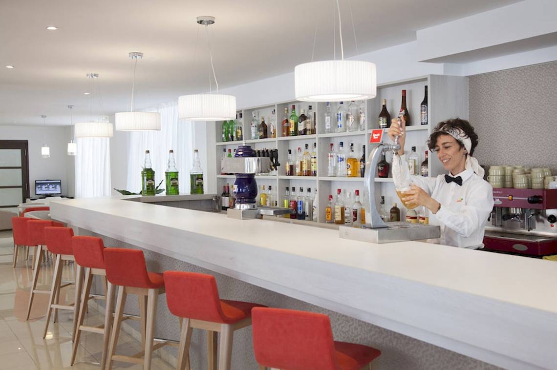 Eine Mitarbeiterin des HSM Venus Playa Hotel serviert ein Getränk an der Bar.