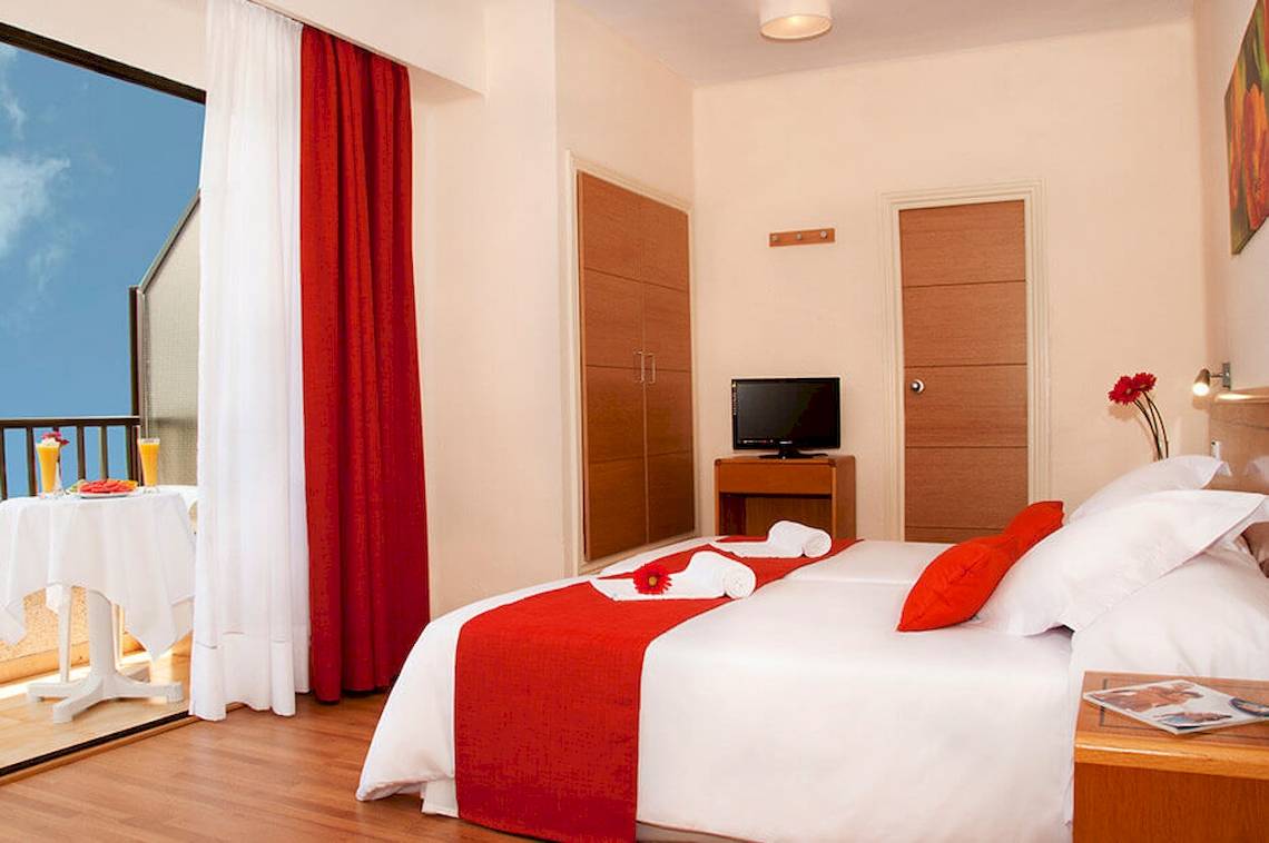 Doppelzimmer im HSM Venus Playa Hotel mit Balkon, zwei Betten, Fernseher und Tisch mit Getränken.
