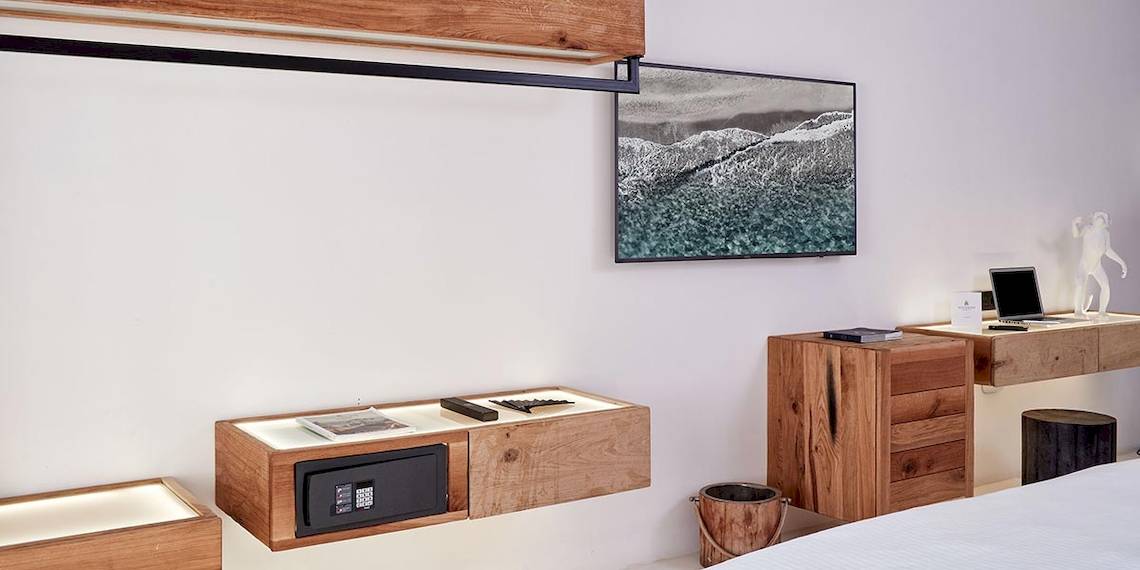 Inneneinrichtung eines Zimmers im Royal Myconian Resort mit Holzmöbeln, Flachbildfernseher, Schreibtisch und Laptop
