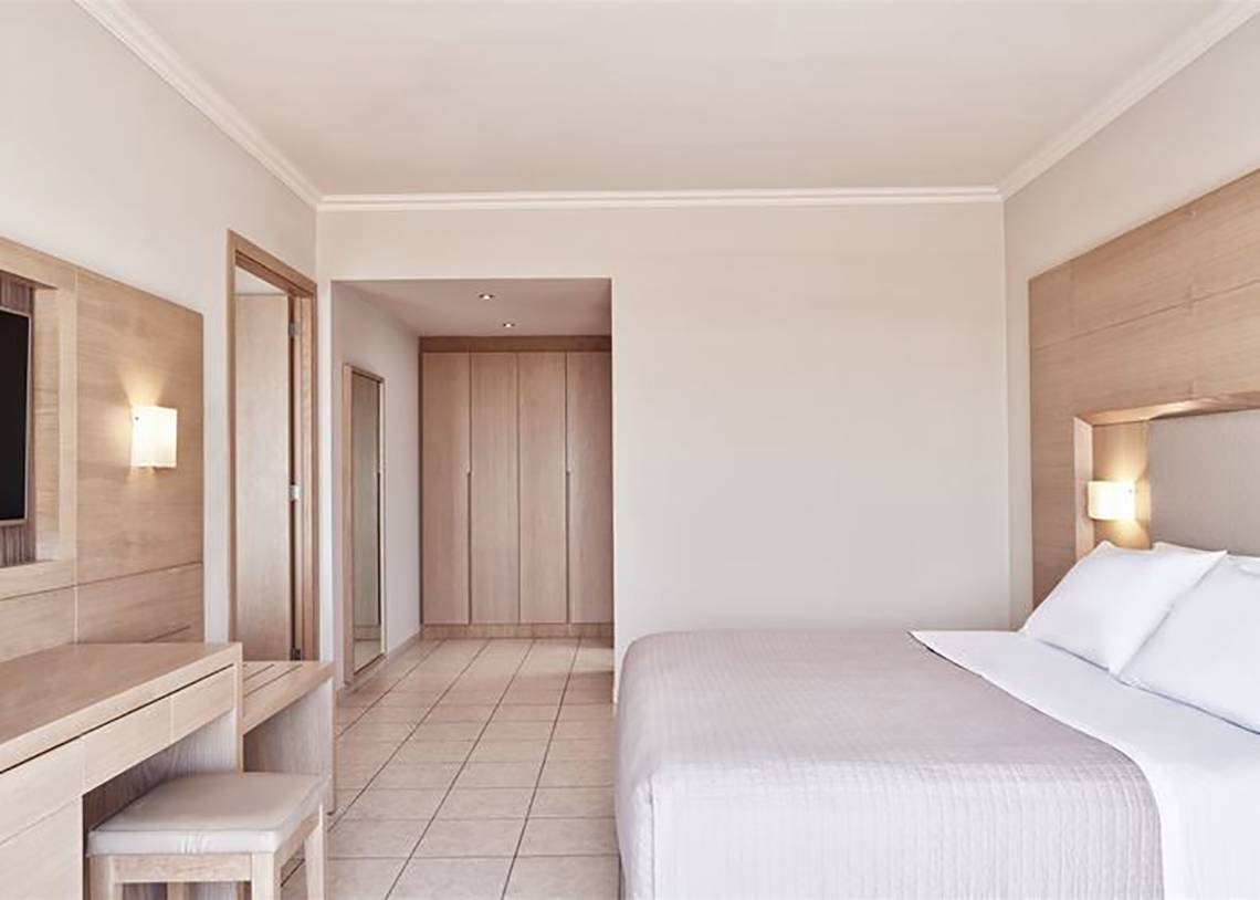 Schlafzimmer im Porto Bello Royal Hotel mit Doppelbett und modernen Holzmöbeln.