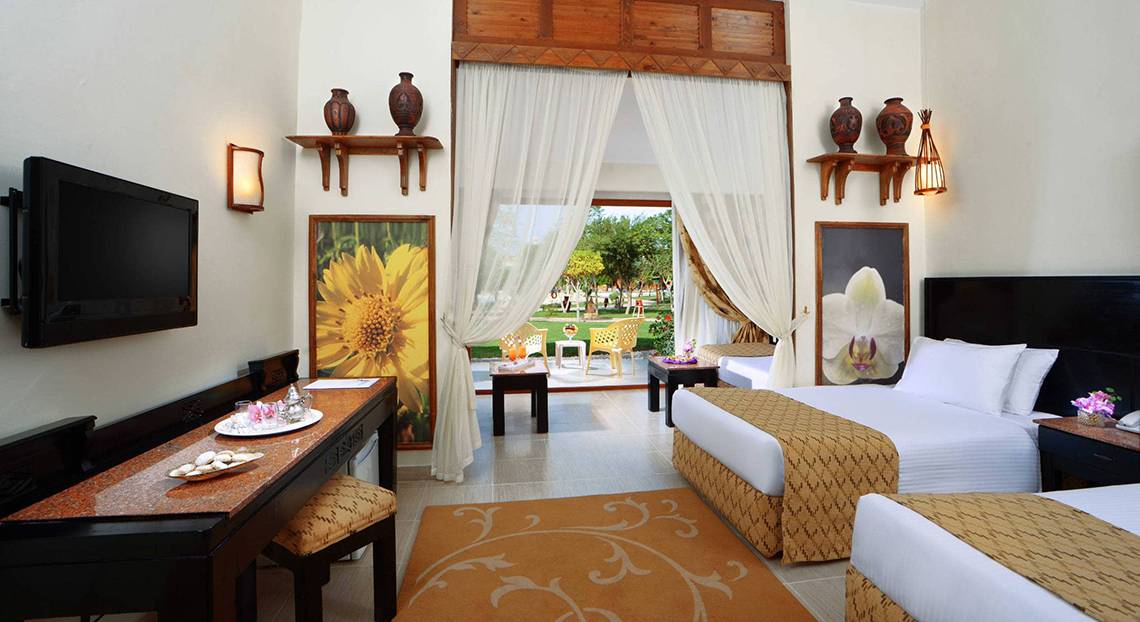 Hotelzimmer im Pickalbatros Jungle Aqua Park Resort mit Fernseher, Tisch und zwei Betten.