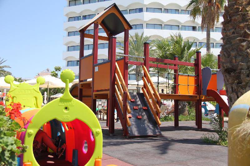 Kinderspielplatz im Freien vor dem Crystal Springs Beach Hotel mit bunten Spielgeräten und Gebäude im Hintergrund.