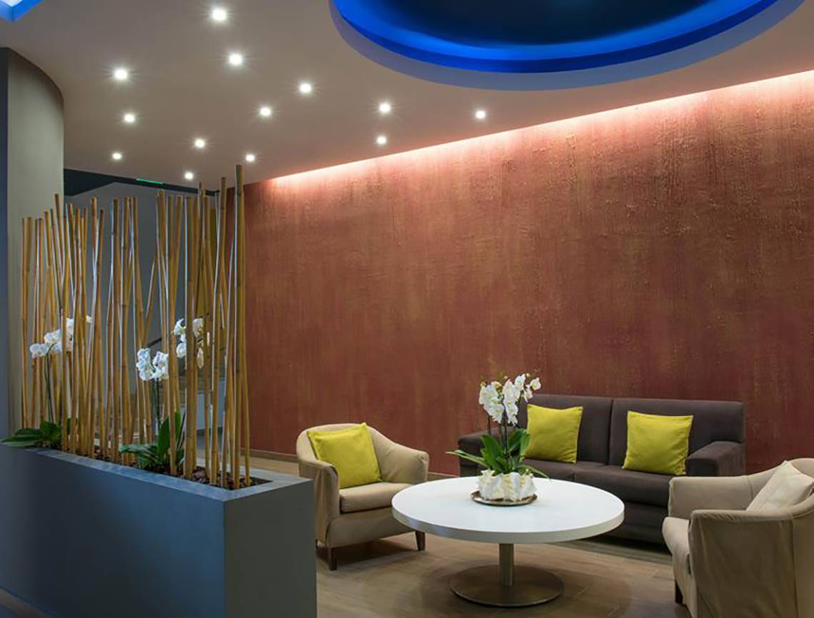 Interieur des Blue Bay Resorts mit einem Sofa, Stühlen und einer Pflanze in der Ecke.