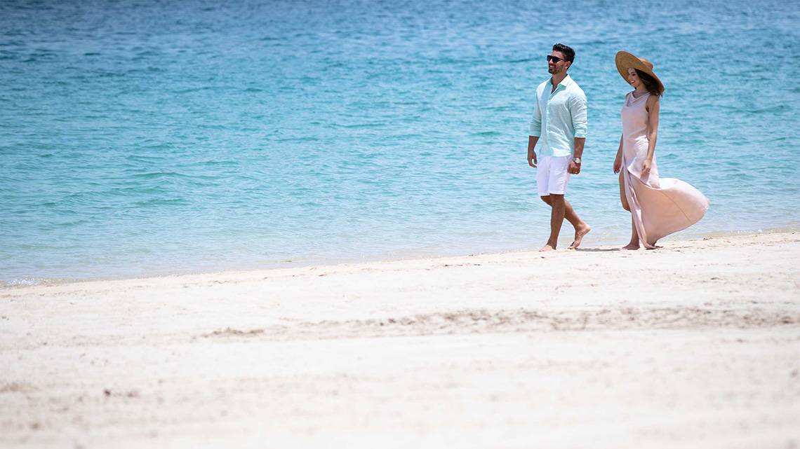 Paar spaziert am Strand vor dem Jumeirah Zabeel Saray Hotel