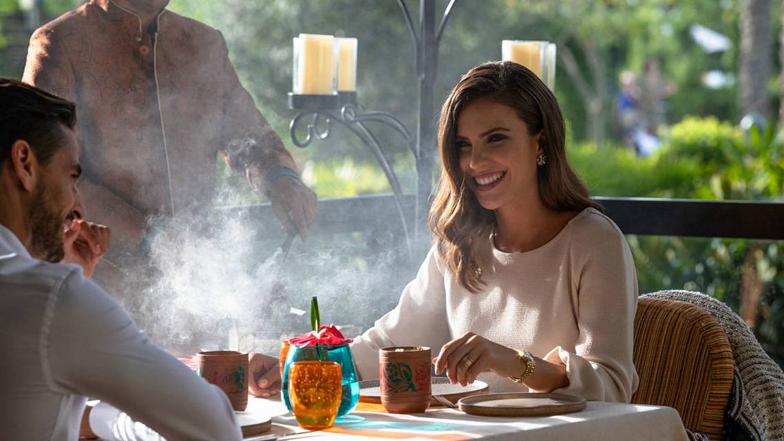 Ein Paar genießt ein Essen im Freien im Jumeirah Zabeel Saray, während ein Kellner im Hintergrund steht.