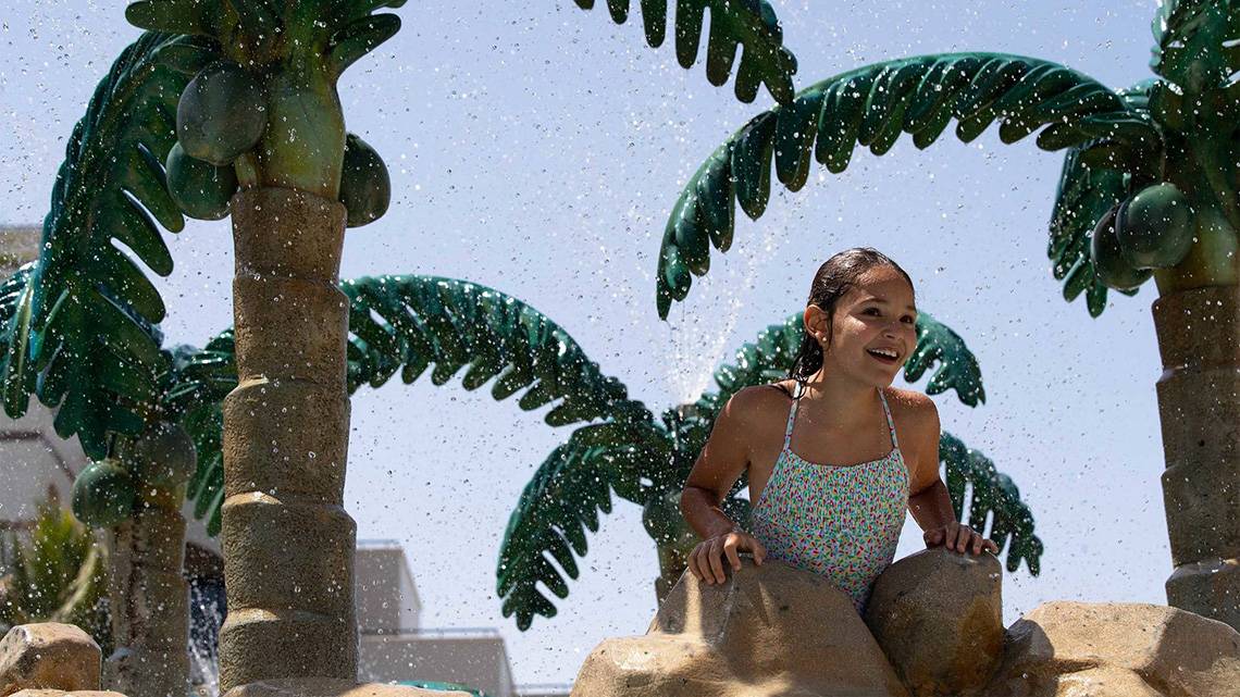 Ein Mädchen, das sich im Wassersprinkler im Jumeirah Zabeel Saray Hotel versteckt.