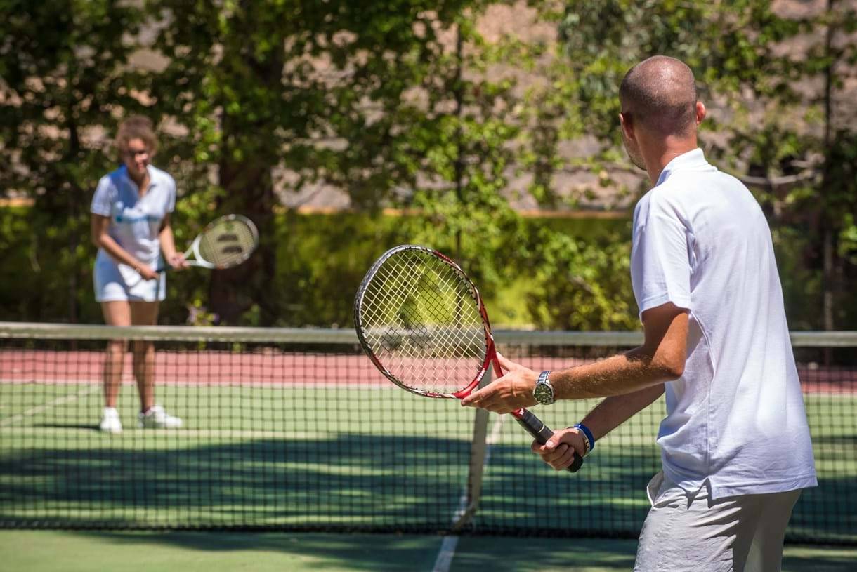 Tennisspieler auf Tennisplatz im Freien mit Frau im Hintergrund