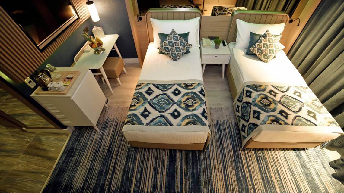 Doppelbett-Zimmer im Royal Wings Hotel mit zwei bequemen Betten, Dekor und Möbeln.