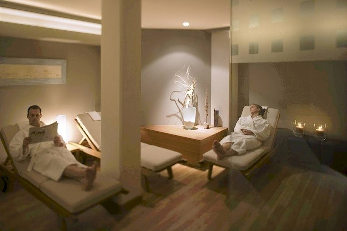Ein Mann liest eine Zeitung auf einem Liegestuhl im Spa des Mövenpick Amsterdam City Centre