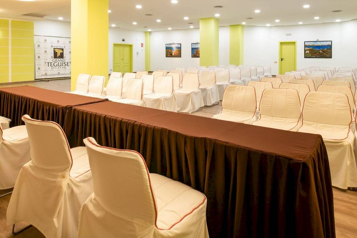 Ein Konferenzraum im Grand Teguise Playa Hotel mit leeren Stühlen und langen Tischen.