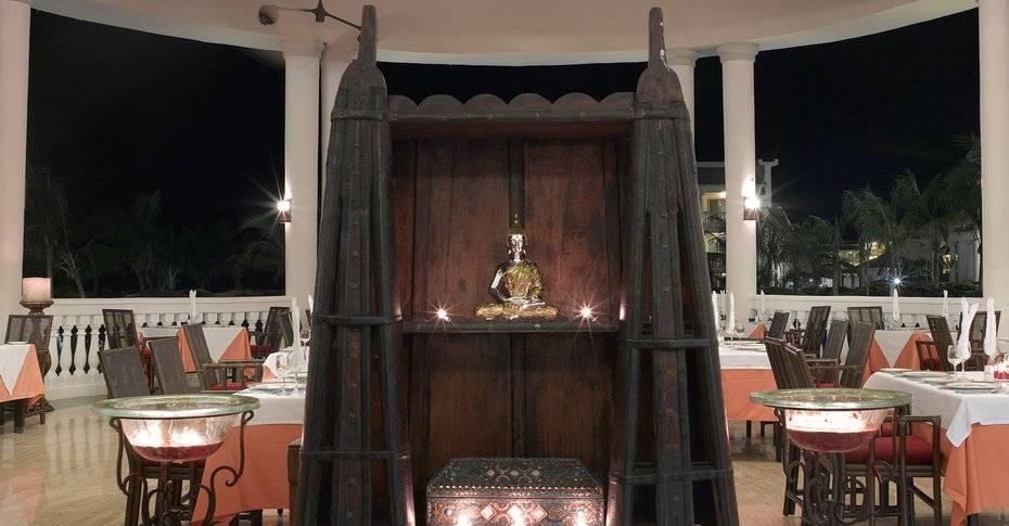Innenbereich des Grand Palladium Jamaica R. & Spa Hotels mit Buddha-Statue und illuminierten Tischen.