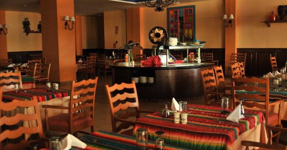 Restaurant im Grand Palladium Jamaica R. & Spa mit farbenfrohen Tischdecken und Holzmöbeln.