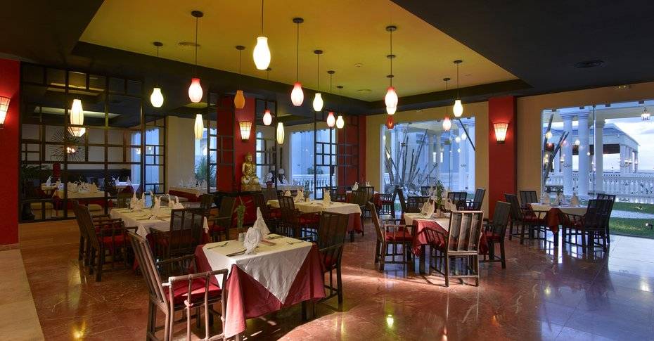 Restaurant im Grand Palladium Jamaica R. & Spa mit gedeckten Tischen und dekorativen Lampen.
