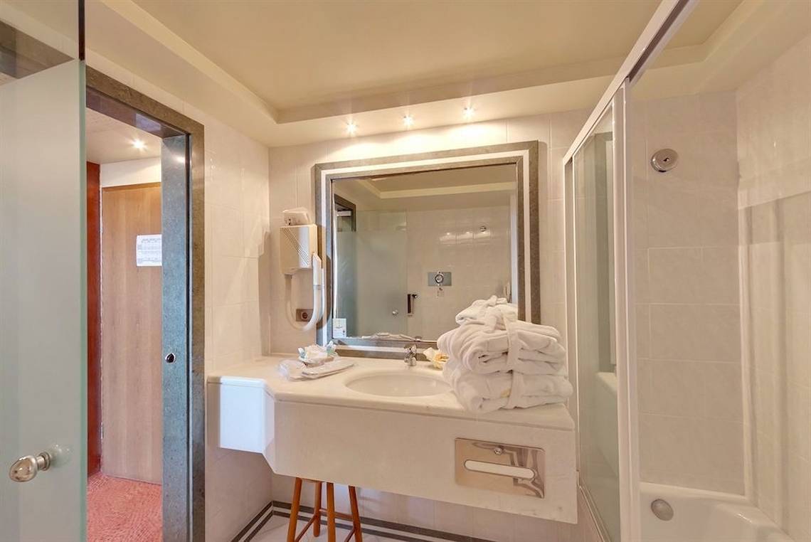 Badezimmer im Possidi Holidays Resort & Suites mit Badewanne, Waschbecken und Handtüchern.