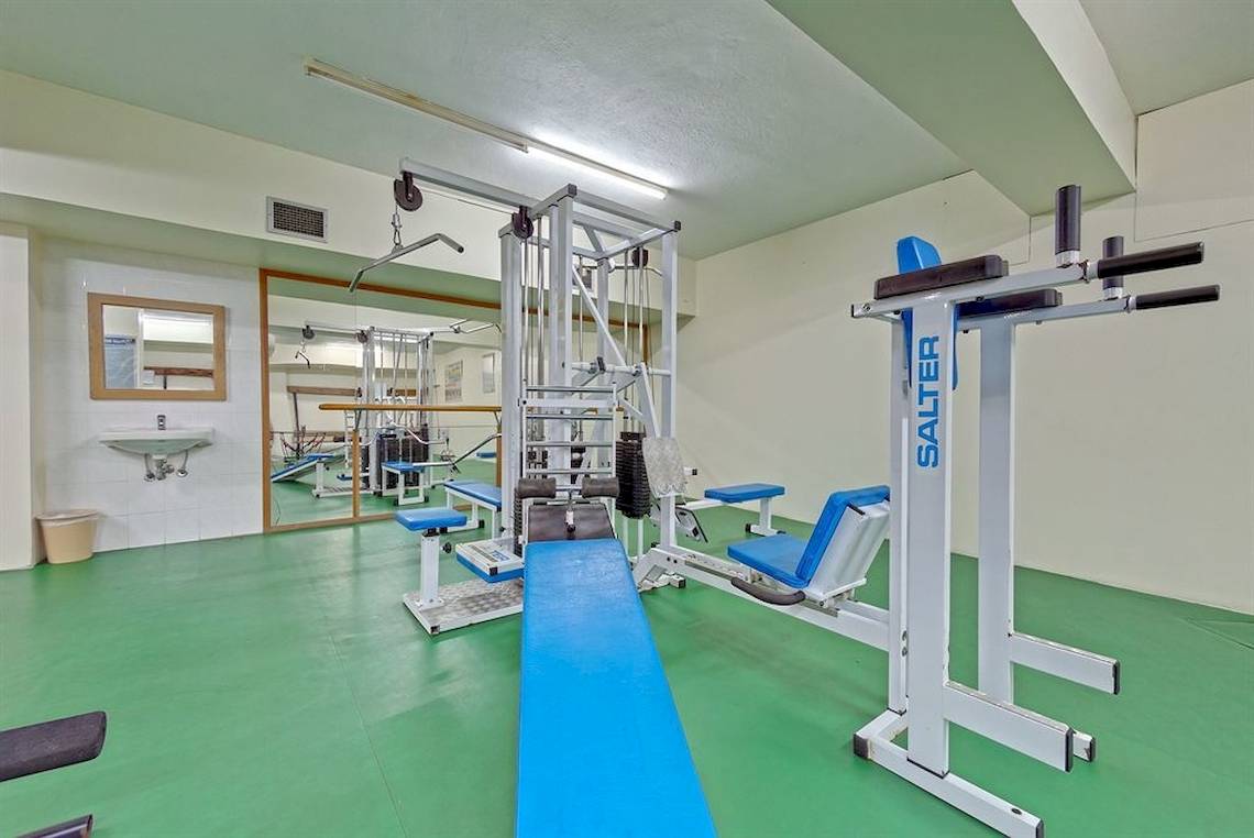 Fitnessraum im Possidi Holidays Resort & Suites mit verschiedenen Trainingsgeräten und grünem Boden.