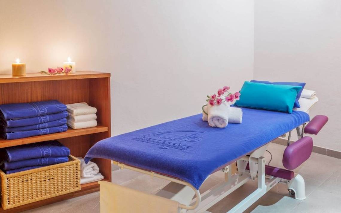Massageraum im Aparthotel Fontanellas Playa mit blauer Decke, Kissen, Kerzen und einem Regal mit Handtüchern.