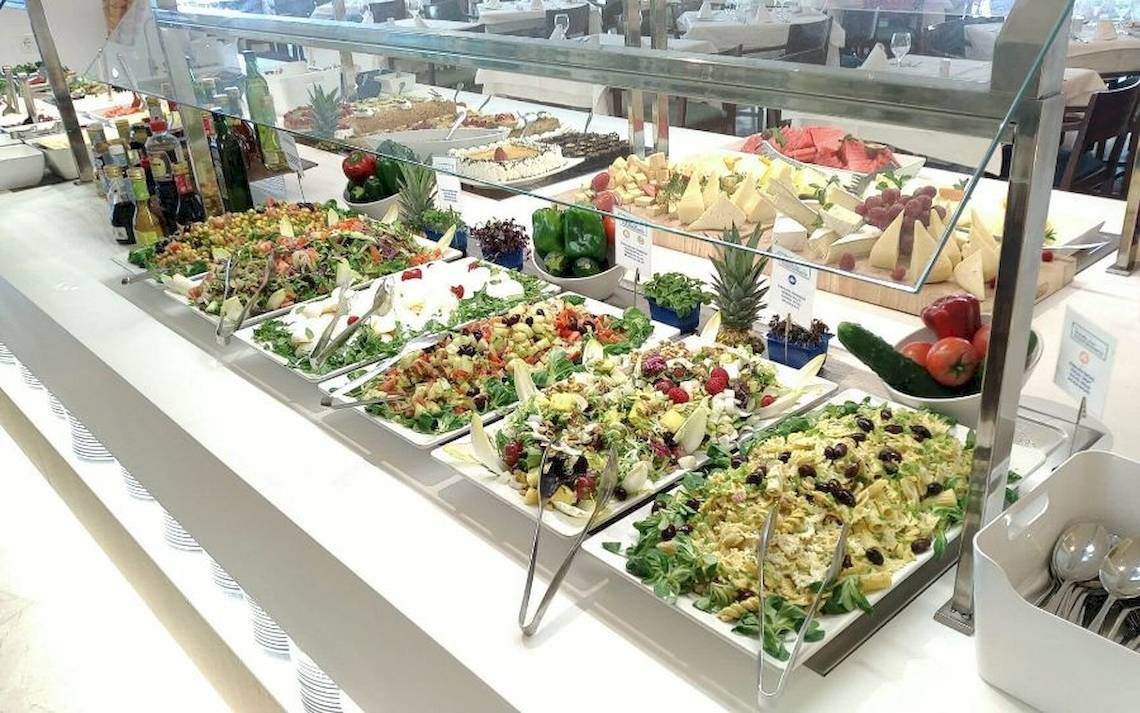 Buffet mit verschiedenen Salaten und Gerichten, darunter Obstsalat, gemischte Salate und Käseplatten.