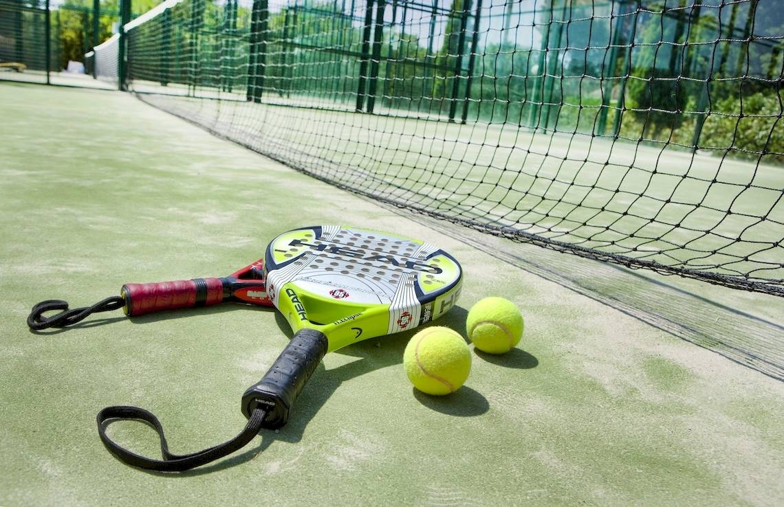 Tennisschläger und Bälle auf einem Tennisplatz neben einem Netz.