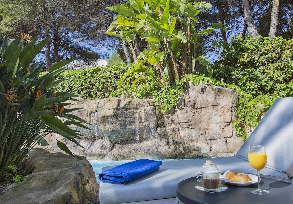Terrasse des Cosmopolitan Hotels mit Pool, Getraenke und einem Blick auf die Natur