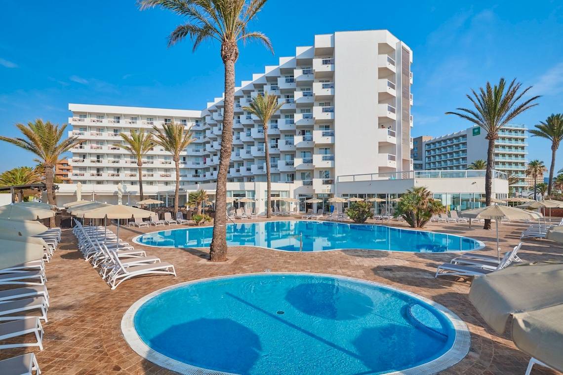 Außenpoolbereich des Hipotels Flamenco Hotels mit Loungestühlen und Sonnenschirmen.