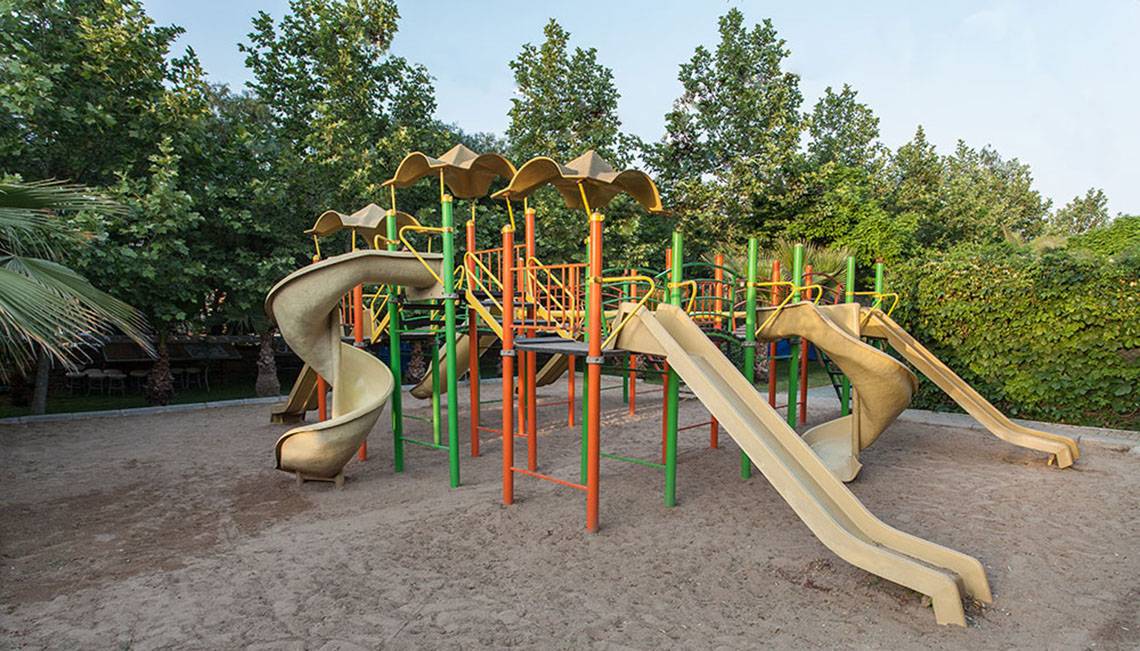Spielplatz im Hotel Sultan of Side mit Rutschen und Klettergerüst unter Bäumen.