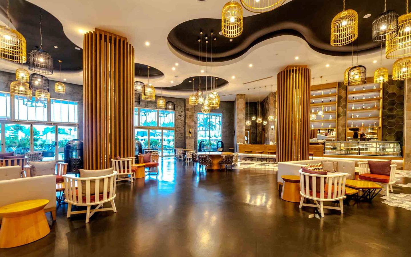 Innenbereich des Sidemarin Kirman Premium Hotels mit Lounge-Stühlen, Tischen und gelben Pendelleuchten.