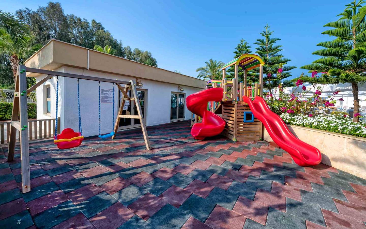 Kinderspielplatz im Hotel Sidemarin Kirman Premium mit roten Rutschen und Schaukeln.