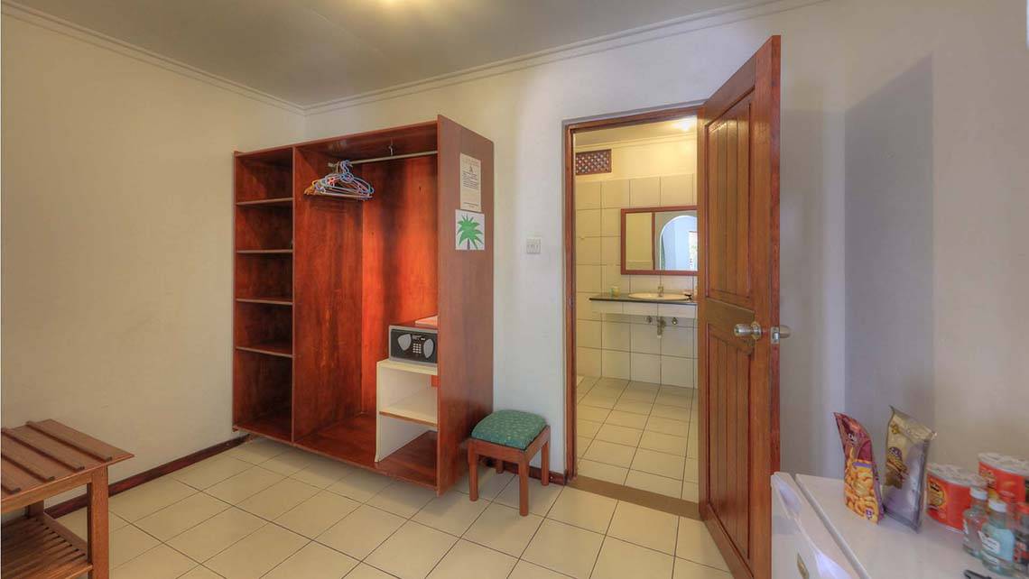 Innenansicht eines Hotelzimmers im Fihalhohi Island Resort, mit Schrank, Safe und offenem Badezimmer.