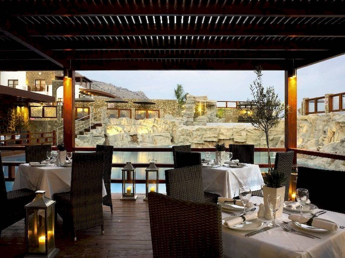 Terrasse des Costa Lindia Beach Resorts mit Blick auf einen Swimmingpool und eine Felslandschaft.