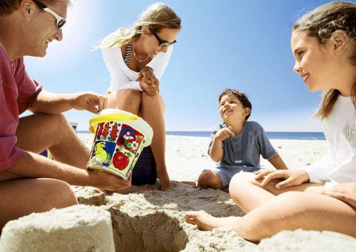 Familie im Costa Lindia Beach Resort am Strand mit Sandburg und Eistüte