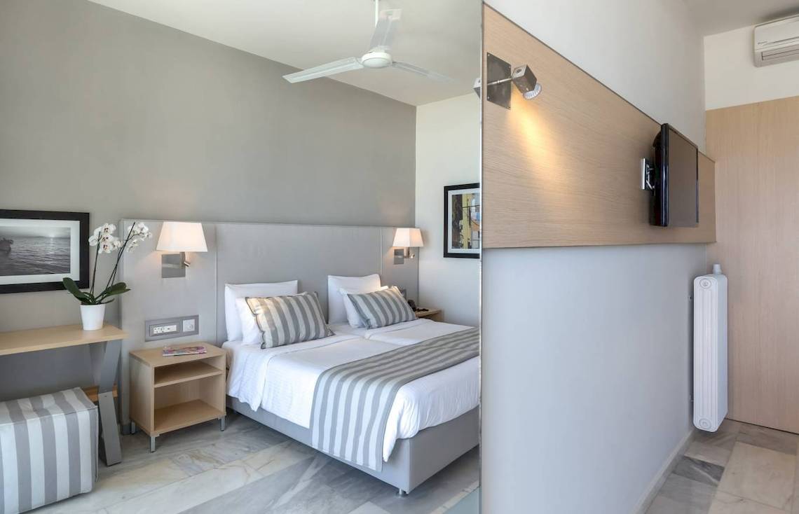 Schlafzimmer im Acharavi Beach Hotel mit Bett, Nachttischen und Klimaanlage.