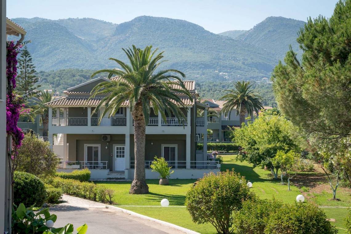 Außenansicht des Acharavi Beach Hotels mit grüner Landschaft und Palmen