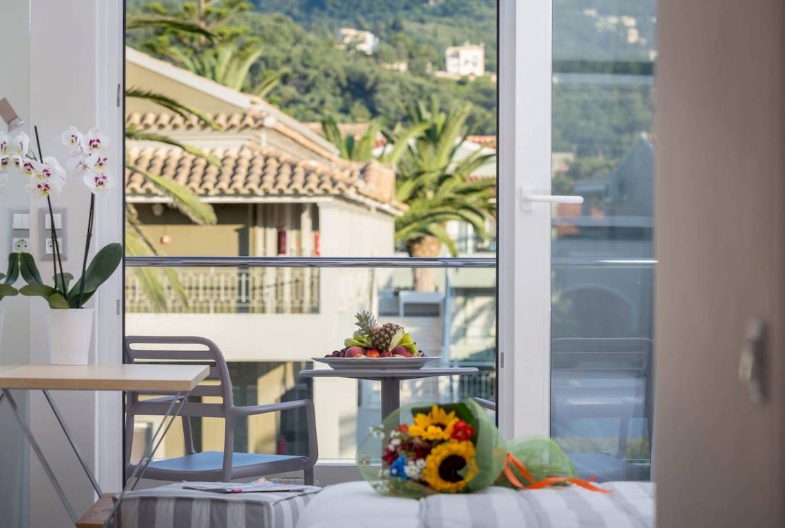 Blick aus dem Hotelzimmer auf eine Terrasse mit Früchten und Blumenstrauß.