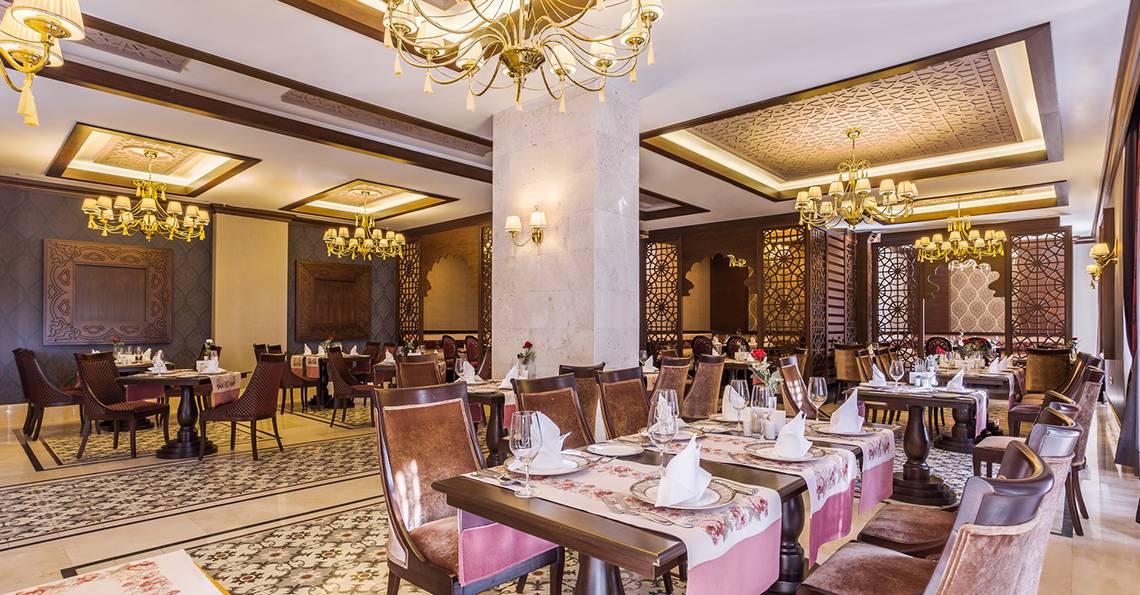 Innenbereich des Restaurants der Villa Side Residence mit reich verzierten Decken und eleganten Tischdekorationen.