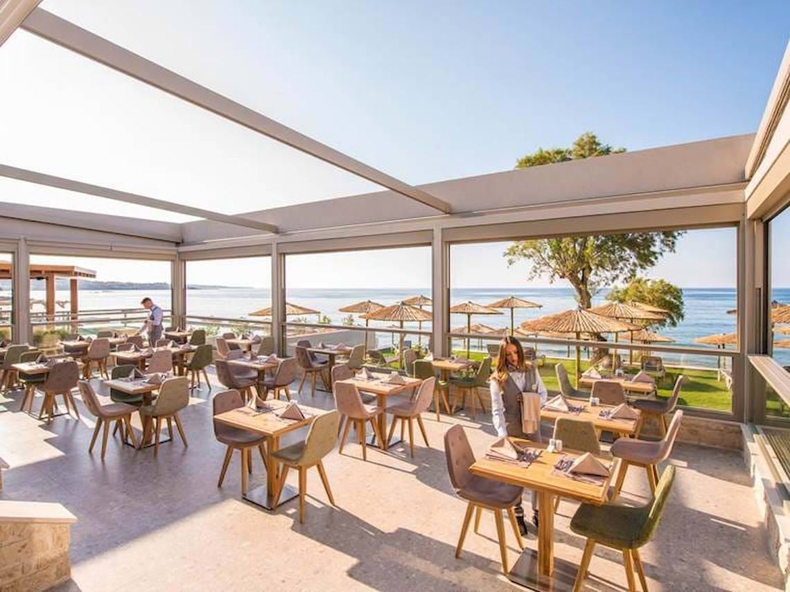 Innenansicht des Restaurants im Cactus Mare Hotel mit Blick auf das Meer und Sonnenschirme.