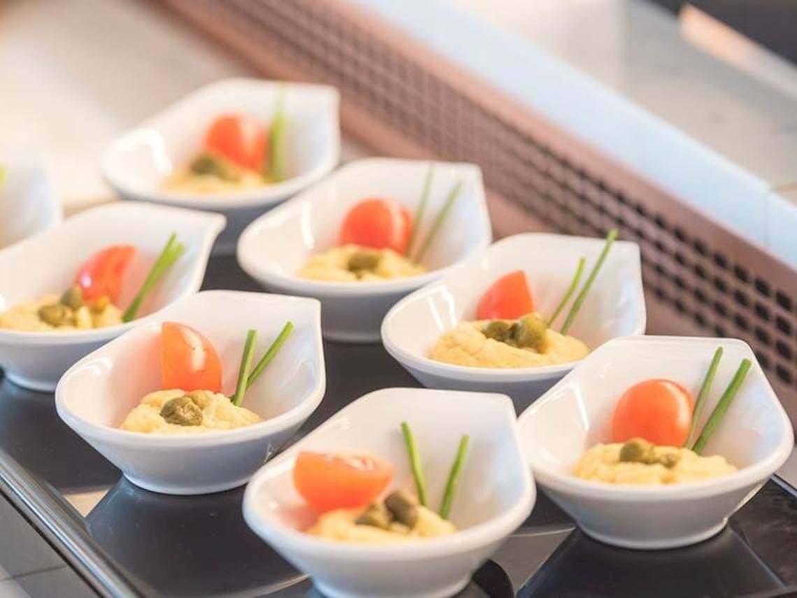Buffet mit kleinen Schüsseln gefüllt mit gelbem Hummus und Tomatenstücken im Cactus Mare Hotel