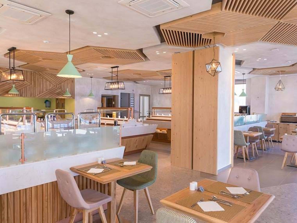 Innenansicht des Cactus Mare Hotel Restaurants mit Holzelementen, hängenden Lampen und gedeckten Tischen.