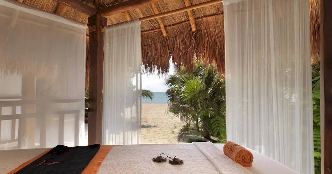 Ein Bett im Hotel Paradisus Playa del Carmen mit Blick auf den Strand und das Meer.