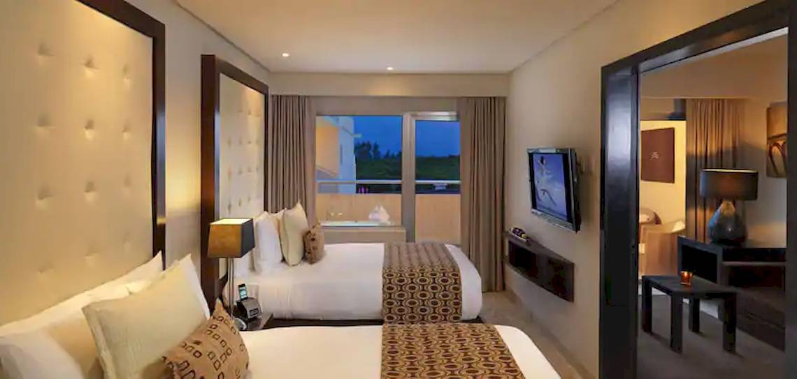 Hotelzimmer im Paradisus Playa del Carmen mit zwei Betten, Fernseher und Balkon.