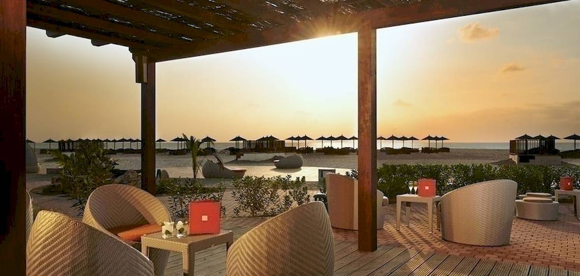 Aussicht auf die Lounge-Ecke am Strand des Melia Athens Hotels mit Sonnenuntergang.