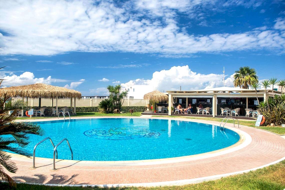 Außenpoolbereich des Plaza Beach Hotels mit Liegestühlen und Sonnenschirmen.