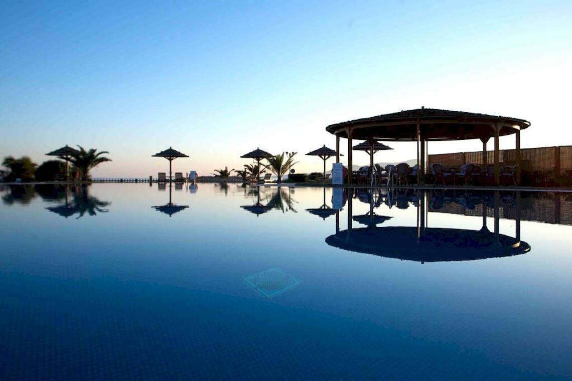 Außenbereich des Plaza Beach Hotel mit Swimmingpool, Sonnenschirmen und Pavillon.