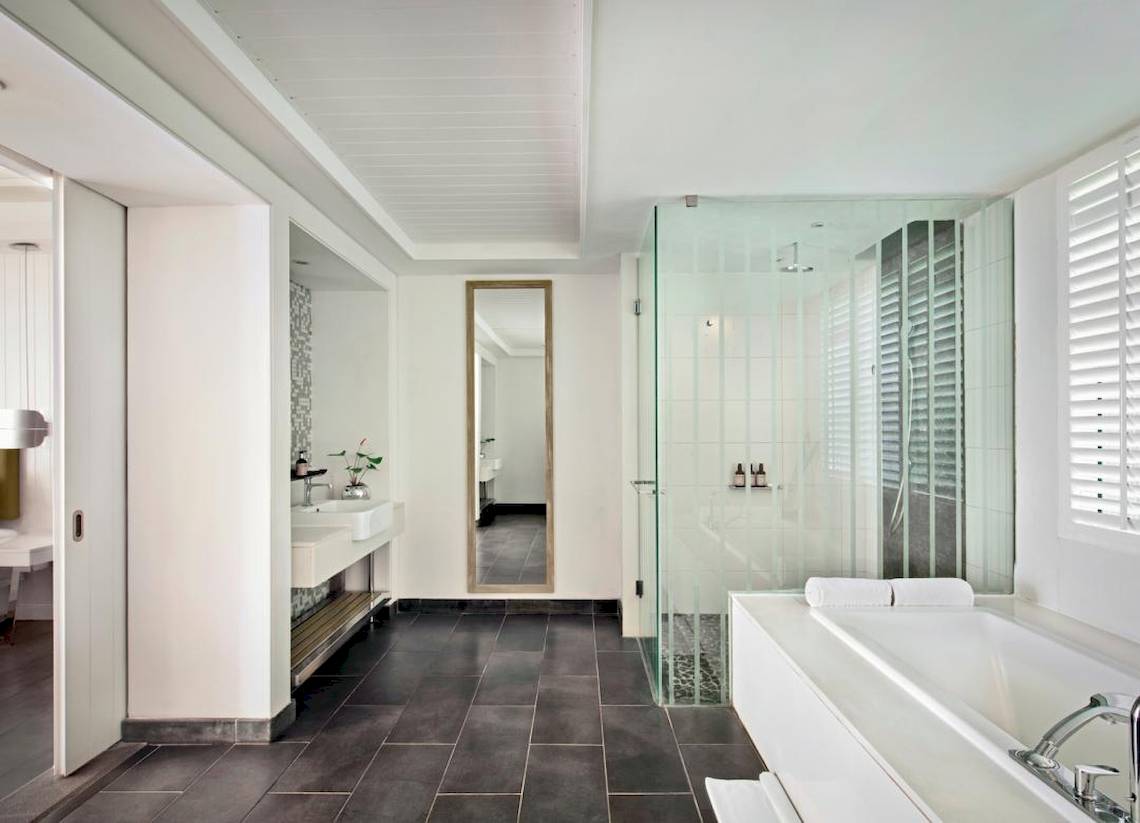 Das Badezimmer im Long Beach Mauritius Hotel mit weißem Wanne, Glasdusche und Waschbecken.
