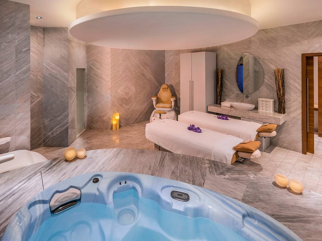 Spa-Bereich im Retreat Palm Dubai MGallery by Sofitel mit Whirlpool, Massageliegen und Marmorboden.