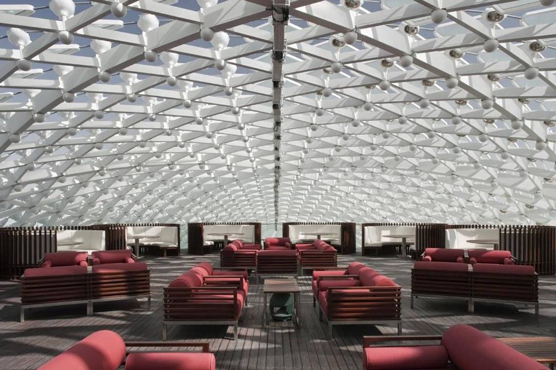 Loungebereich des W Abu Dhabi Hotels auf Yas Island mit roten Sesseln und weißer Dachstruktur.