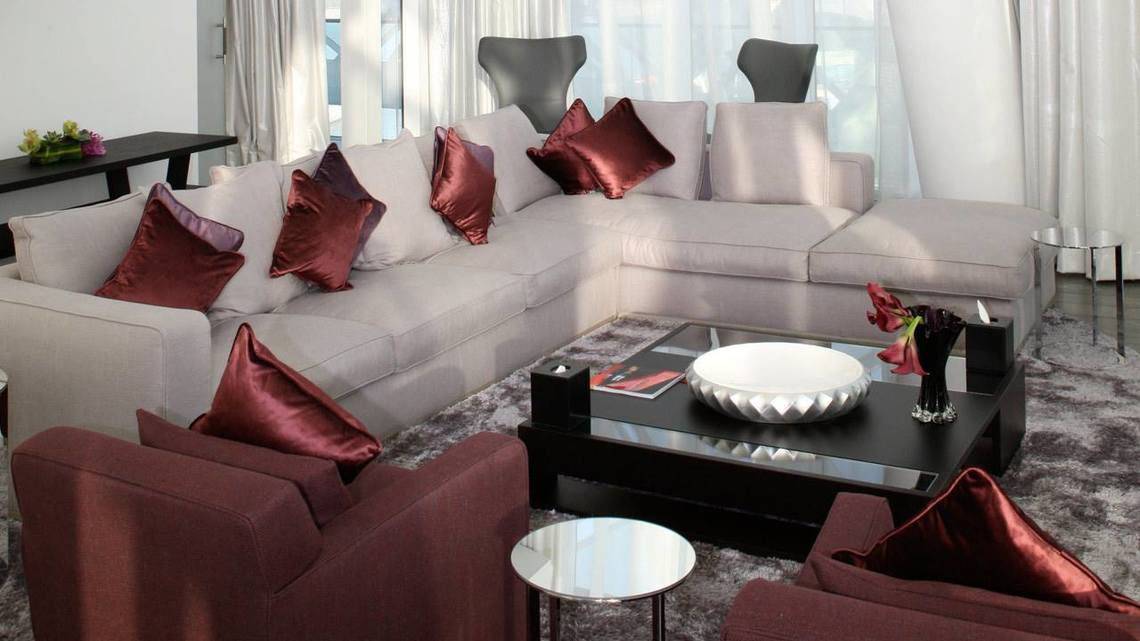 Modernes Wohnzimmer mit großem Sofa, roten Kissen und Glastisch im W Abu Dhabi - Yas Island Hotel.